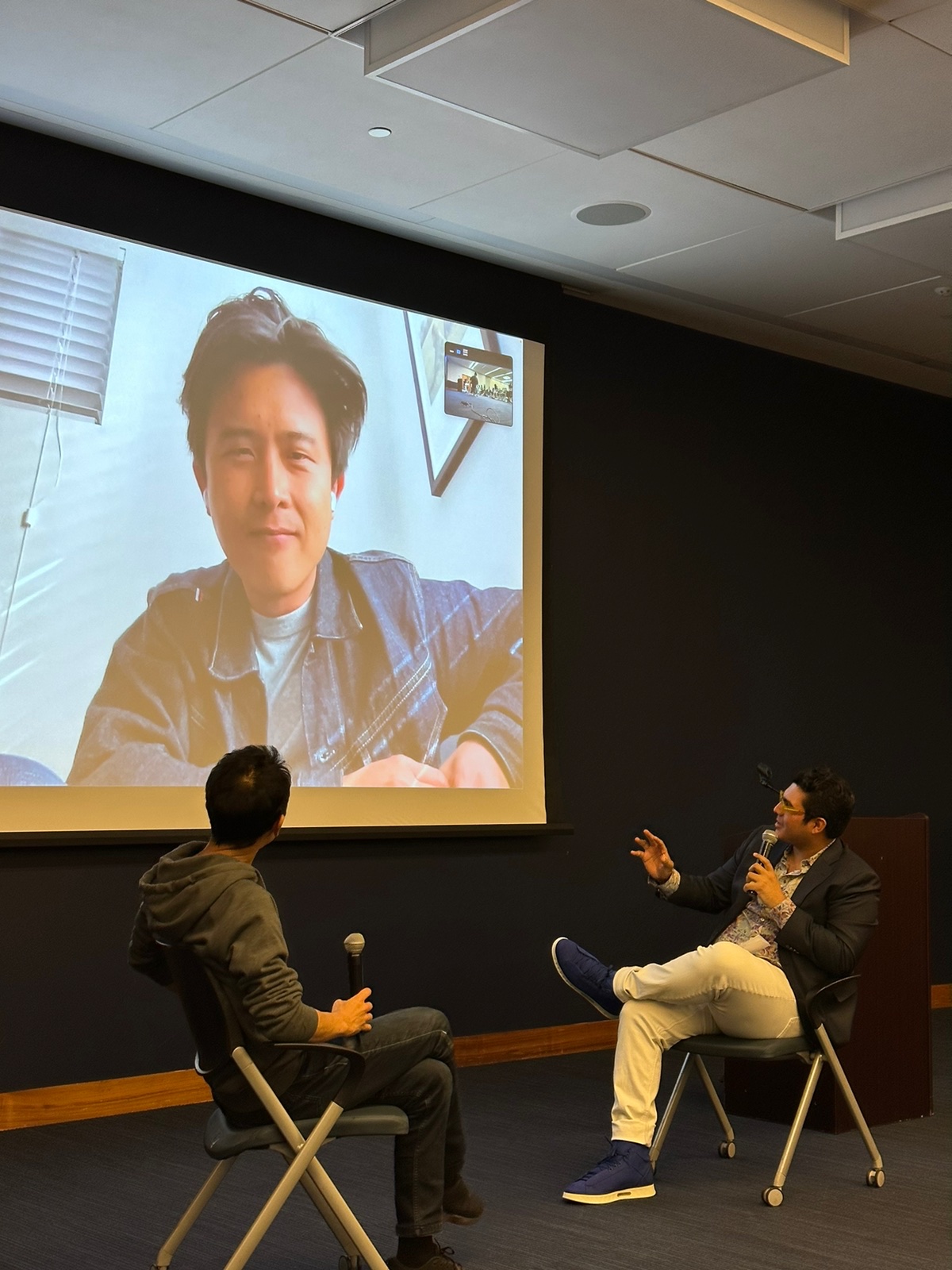 Salomón moderating a filmmaker Q&A over a video call projected on a screen