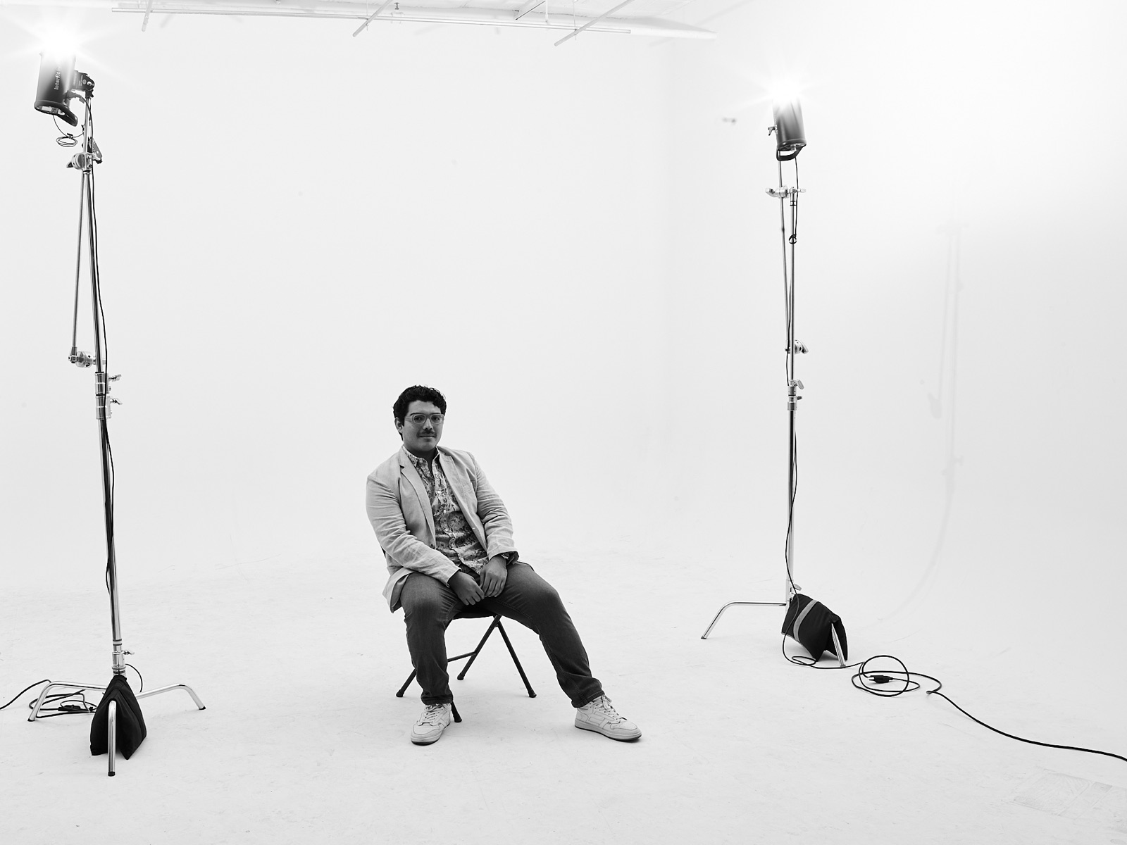 Black-and-white studio portrait of Salomón seated between two studio lights